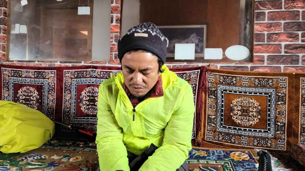 A trekker resting after experiencing symptoms of Acute Mountain Sickness (AMS).