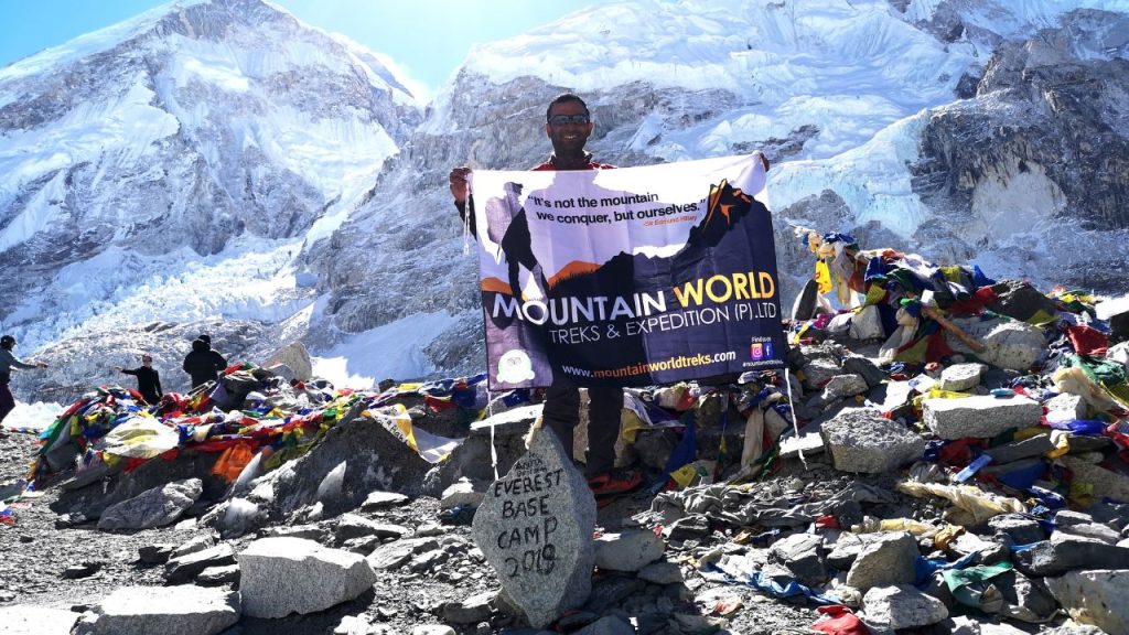 Saligram Aryal holding a Mountain World Treks banner at Everest Base Camp