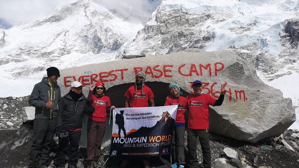 Trekkers at Everest Base Camp holding a Mountain World Treks banner